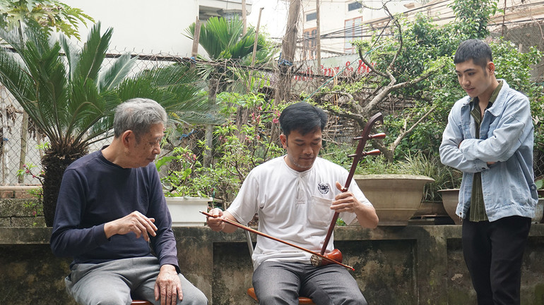 Nghệ nhân Hoàng Văn Hởi (bên trái) chia sẻ về một ngón đàn.