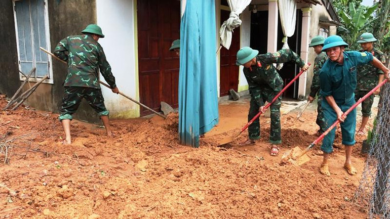 Các lực lượng giúp dân dọn bùn, đất đá tràn vào nhà do sạt lở núi tại huyện Phú Lộc.