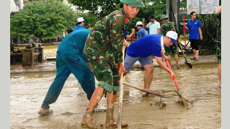 Lực lượng vũ trang tỉnh huy động cán bộ, chiến sĩ cùng thanh niên trong tỉnh dọn bùn, vệ sinh các tuyến đường tại thành phố Huế sau khi nước lũ rút ra.