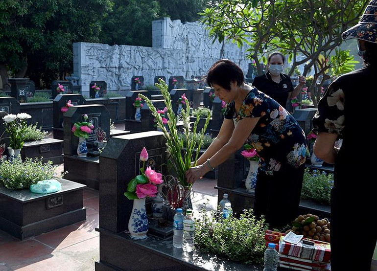 Thân nhân một gia đình liệt sĩ chuẩn bị hương hoa dâng lên phần mộ tại nghĩa trang Mai Dịch.