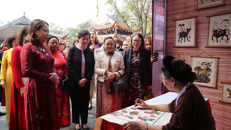 Các đại biểu xem và tham gia trải nghiệm làm tranh dân gian Đông Hồ.