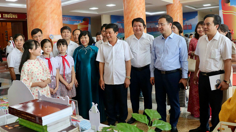 Các em học sinh hào hứng giới thiệu sách tới đại biểu tham dự Tuần lễ hưởng ứng học tập suốt đời.