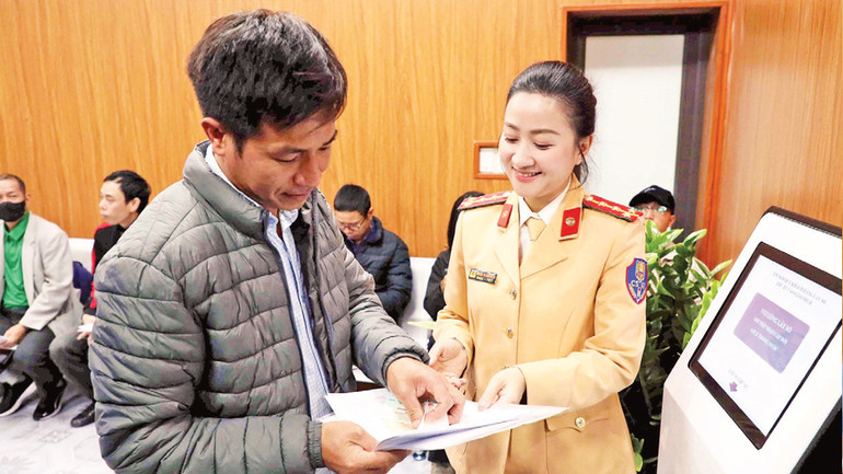 Hướng dẫn người dân lấy số thứ tự để làm thủ tục cấp, đổi giấy phép lái xe.