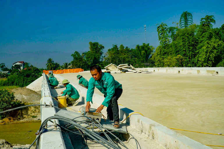 Công nhân Công ty TNHH Xây dựng - Thương mại số 6 tỉnh Điện Biên hoàn thiện các hạng mục cuối trong dự án cầu Pom La bắc qua sông Nậm Rốm.