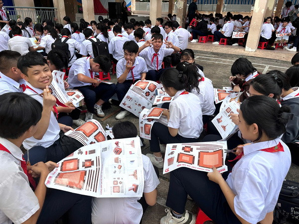 Học sinh hào hứng cắt, dán mô hình Cột cờ Hà Nội của phụ san Báo Nhân Dân.