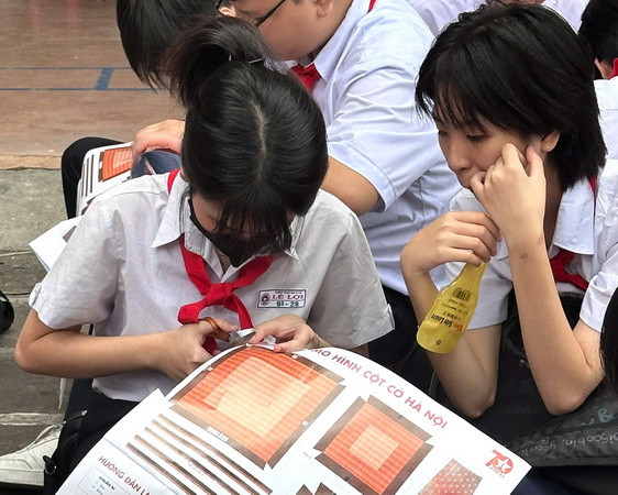 Học sinh cẩn thận cắt phụ san Cột cờ Hà Nội của Báo Nhân Dân để dán thành mô hình.