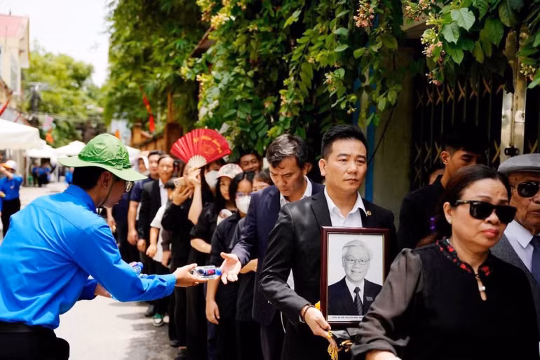 Thanh niên tình nguyện tiếp nước phục vụ người dân đến viếng Tổng Bí thư Nguyễn Phú Trọng tại quê hương Lại Đà, xã Đông Hội, huyện Đông Anh.