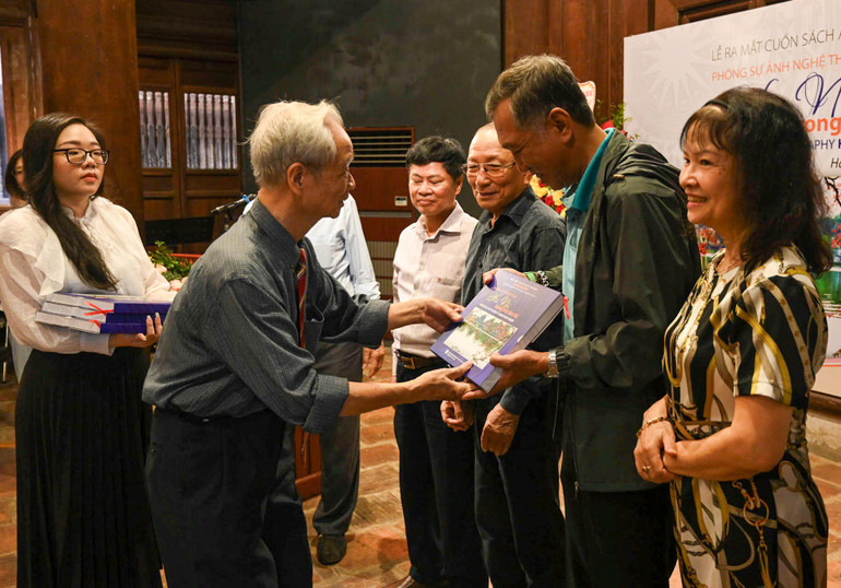 Nghệ sĩ nhiếp ảnh Nguyễn Văn Phúc trao tặng sách cho các đại biểu. (Ảnh: DUY LINH).