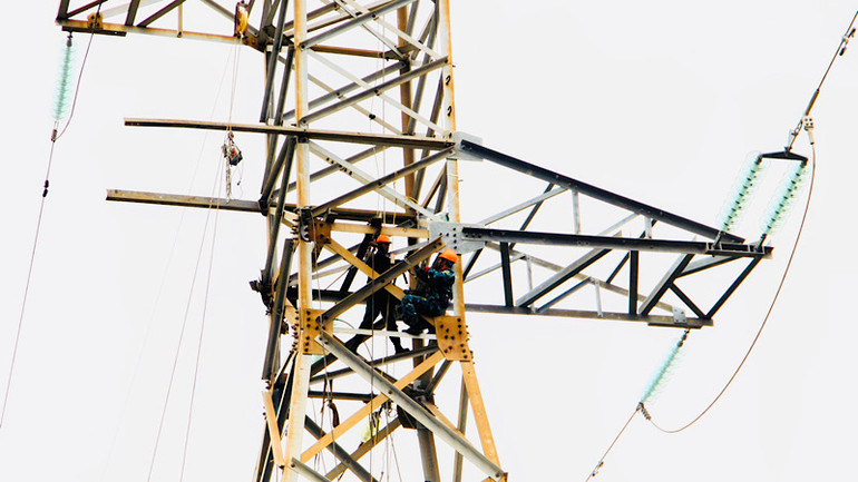 Công nhân Điện lực Hải Phòng làm việc trên cao trong thời tiết có mưa và gió lớn.