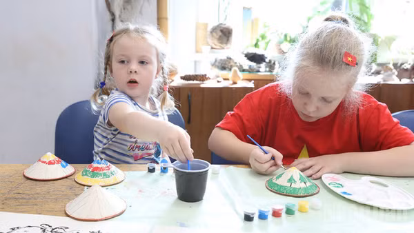 Các “nghệ nhân nhí” say sưa tô vẽ những chiếc nón lá Việt Nam.