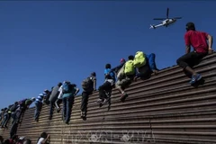 Người di cư trèo qua bức tường biên giới Mexico-Mỹ, gần cửa khẩu El Chaparral ở Tijuana, bang Baja California, Mexico. (Ảnh tư liệu: TTXVN)