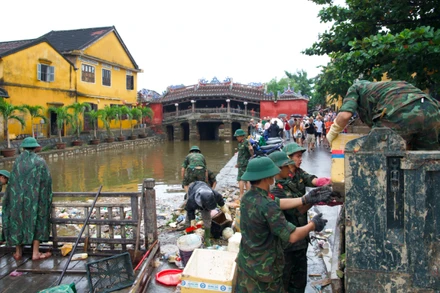 Các cán bộ, chiến sĩ Trường Quân sự Quân khu 5 thu dọn và vận chuyển lượng lớn rác tích tụ tại khu vực chùa Cầu Hội An sau lũ.