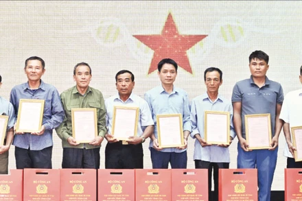 Đại diện các gia đình liệt sĩ Viện K20 nhận Thông báo kết quả giám định ADN hài cốt liệt sĩ. (Ảnh TRẦN HẢI)