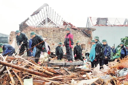 Các lực lượng hỗ trợ người dân thu dọn tài sản sau khi trận giông lốc tối 25/8 làm sập đổ nhà dân ở phường Lý Thường Kiệt, tỉnh Ninh Bình.