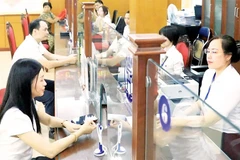 Giải quyết thủ tục hành chính cho người dân tại điểm phục vụ hành chính công phường Thanh Xuân. (Ảnh QUANG THÁI)