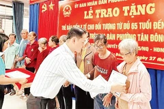 Trao thẻ Bảo hiểm y tế cho người cao tuổi phường Tân Đông Hiệp. (Ảnh: VÕ LÊ)