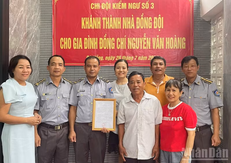 Đồng chí Vũ Văn Tài, Bí thư Đảng ủy Chi đội Kiểm ngư số 3 (thứ hai từ trái sang) trao kinh phí hỗ trợ nhà đồng đội cho gia đình đồng chí Nguyễn Văn Hoàng. (Ảnh: TIẾN DŨNG)