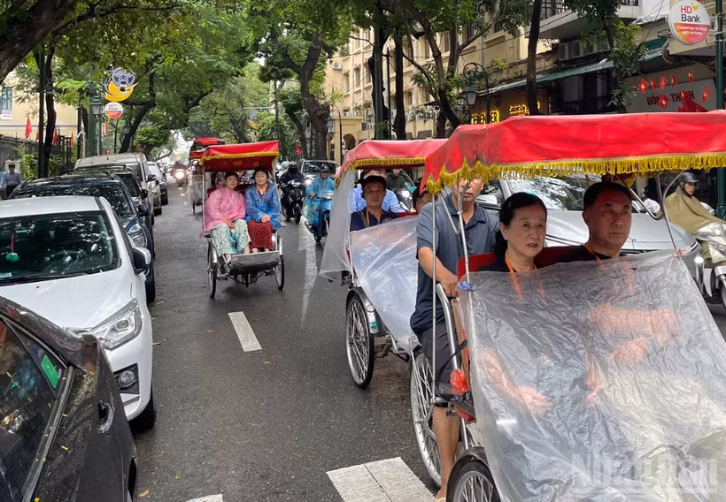 Du khách nước ngoài trên phố Tràng Thi (Hà Nội) ngày mưa. (Ảnh minh họa: Đ.T)