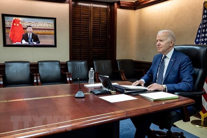 Tổng thống Mỹ Joe Biden và Chủ tịch Trung Quốc Tập Cận Bình (trên màn hình) tại cuộc họp trực tuyến ngày 18/3/2022. (Ảnh: AFP/TTXVN)