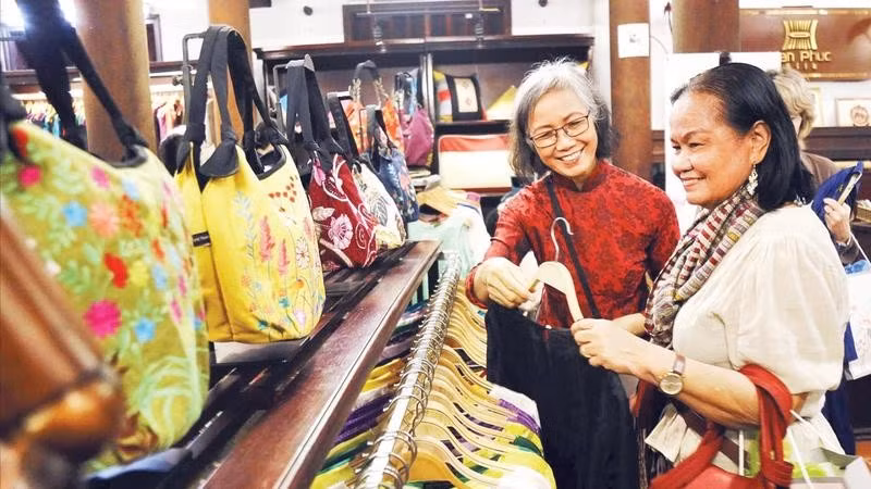 Khách du lịch mua hàng tại một cửa hàng giới thiệu sản phẩm làng nghề dệt lụa Vạn Phúc.