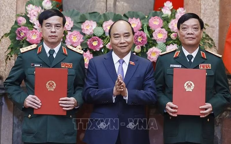 Chủ tịch nước Nguyễn Xuân Phúc, Thống lĩnh các lực lượng vũ trang nhân dân, Chủ tịch Hội đồng Quốc phòng và An ninh trao Quyết định thăng quân hàm từ Trung tướng lên Thượng tướng đối với đồng chí Ngô Minh Tiến và Lương Đình Hồng. (Ảnh: TTXVN)