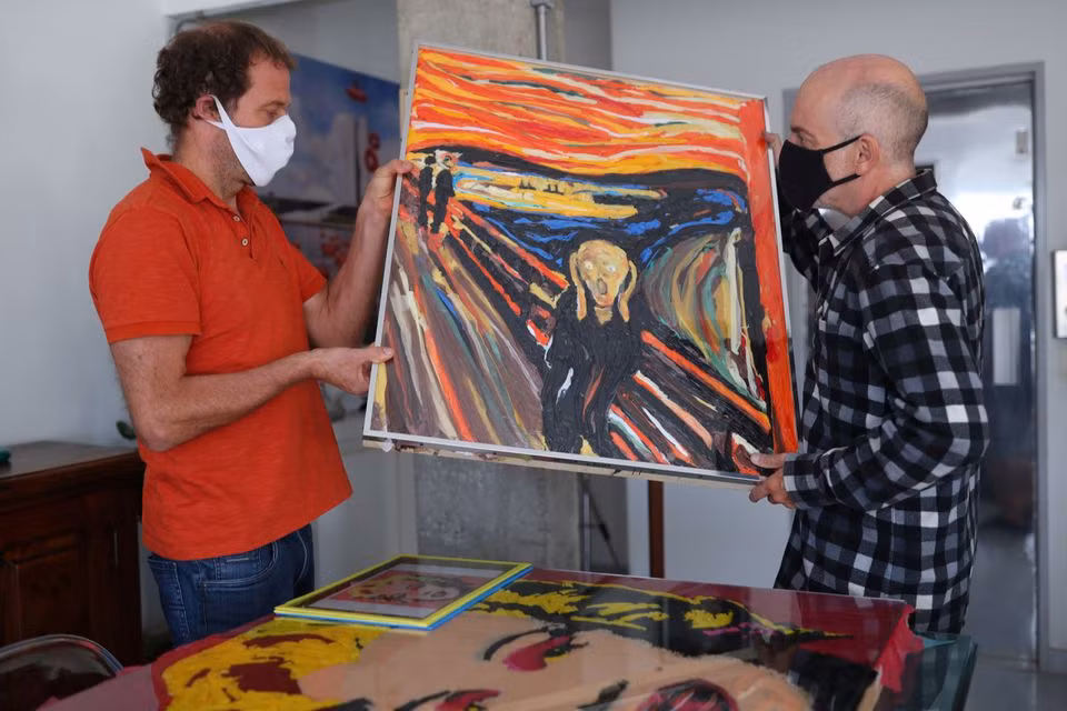 Nghệ sĩ Brazil Eduardo Srur và trợ lý Rogerio Canella đã tái hiện bức tranh “Tiếng thét” của Edvard Munch từ rác nhựa trong loạt triển lãm “Thiên nhiên nhựa” tại phòng tranh của ông ở Sao Paulo, Brazil ngày 27-5. Ảnh: Reuters.