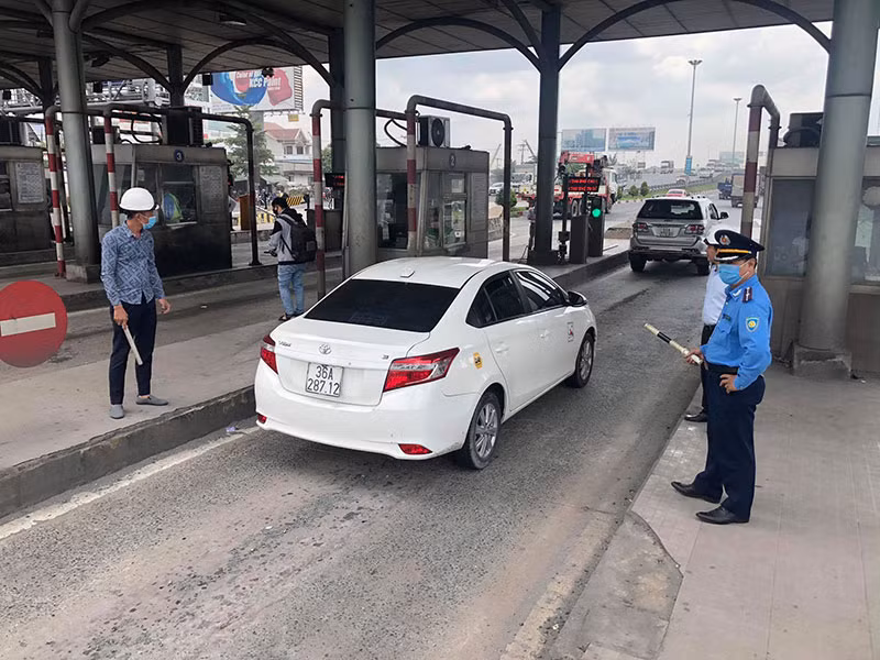 Lực lượng chức năng hướng dẫn xe qua trạm sau khi tạm dừng thu phí.