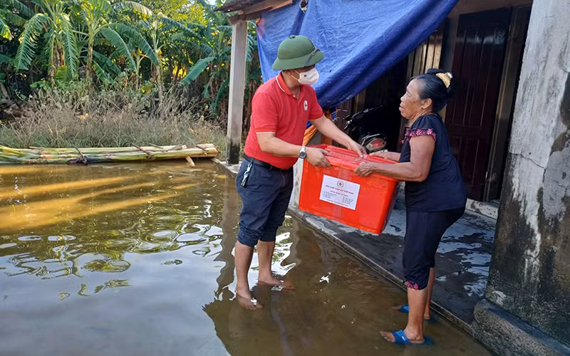 Đại diện Hội Chữ thập đỏ tỉnh Quảng Bình trao thùng hàng hỗ trợ hộ dân bị ảnh hưởng mưa, lũ tại xã Tân Ninh, huyện Quảng Ninh. (Ảnh PHƯƠNG DUNG)