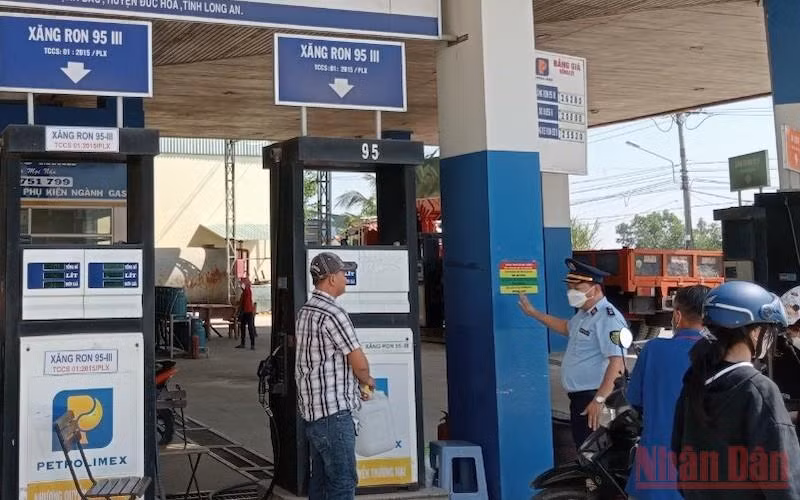 Lực lượng quản lý thị trường tỉnh Long An kiểm tra, giám sát và dán thông tin số điện thoại đường dây nóng để tiếp nhận phản ánh của người dân tại cửa hàng xăng, dầu Quốc Minh, xã Mỹ Hạnh Bắc, huyện Đức Hoà, tỉnh Long An.