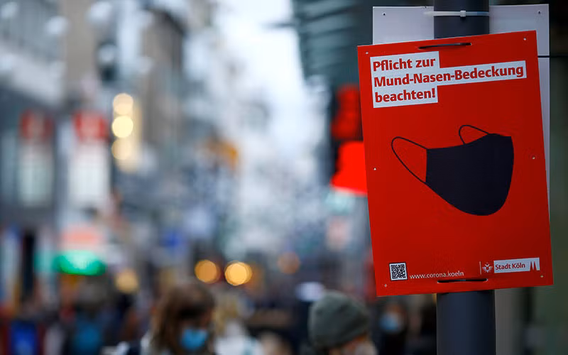 Biển nhắc nhở người dân che miệng và mũi trên phố mua sắm Strasse tại TPCologne, Đức, tháng 12/2021. (Ảnh: Reuters)
