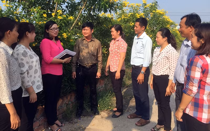 Bí thư Ðảng ủy xã Bình Hiệp Bùi Thùy Trang (người đeo kính) trao đổi cùng người dân về công tác xây dựng nông thôn mới.