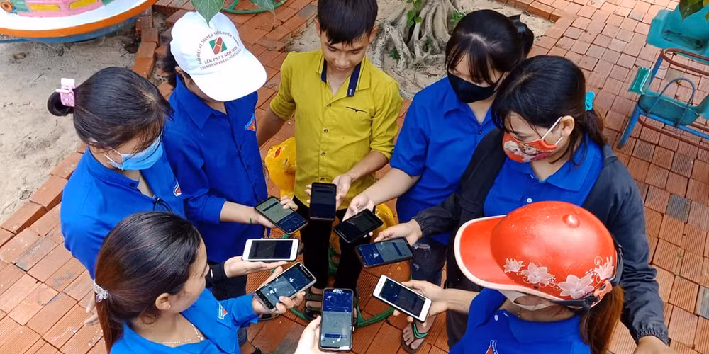 Thanh niên tình nguyện và người dân cùng cài đặt ứng dụng Bluezone ở Gia Lai.
