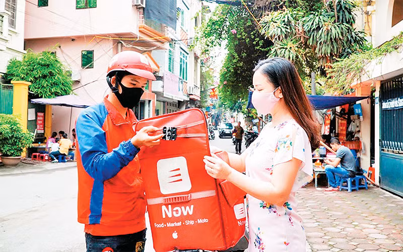 Nhân viên một sàn thương mại điện tử giao hàng cho khách. (Ảnh NGỌC CHÂU) 