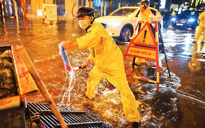 Công nhân Xí nghiệp thoát nước số 1, Công ty TNHH một thành viên Thoát nước Hà Nội ứng trực tại một điểm úng ngập trên địa bàn quận Hoàn Kiếm. (Ảnh: THÀNH ĐẠT)
