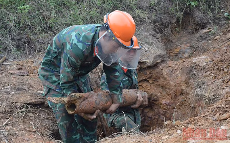 Lực lượng chức năng tiến hành rà phá vật nổ trong vườn nhà ông Nguyễn Văn Nho.