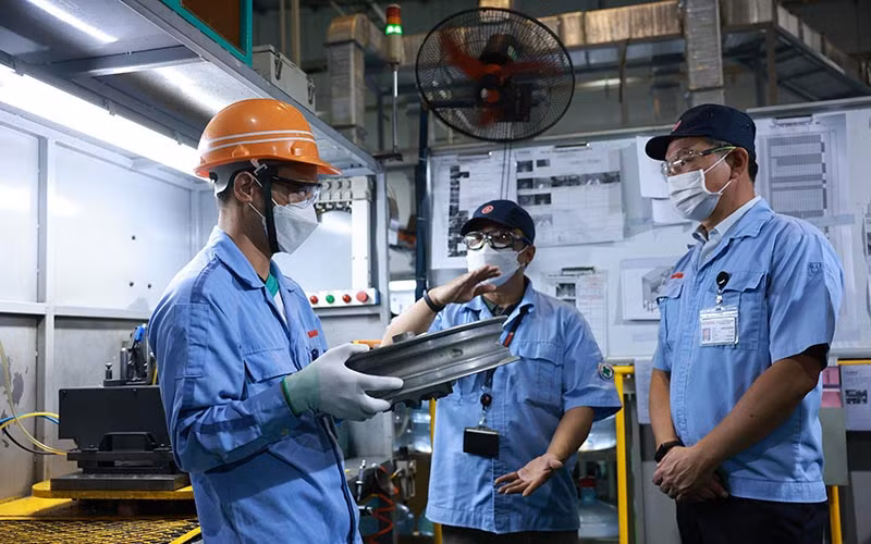 Công nhân Phạm Văn Tư (ngoài cùng bên trái) trao đổi ý tưởng cải tiến sản phẩm với lãnh đạo Công ty TNHH Sản xuất phụ tùng Yamaha Motor Việt Nam. (Ảnh Đình hải)
