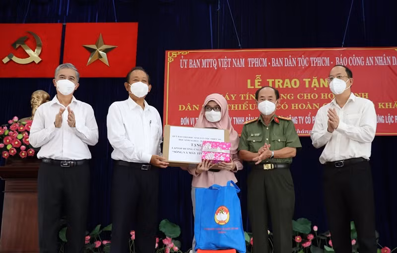 Nguyên Phó Thủ tướng Thường trực Chính phủ Trương Hòa Bình (thứ 2 từ trái qua) và đại diện các đơn vị trao tặng thiết bị học tập trực tuyến cho các em học sinh dân tộc Chăm tại quận 8.