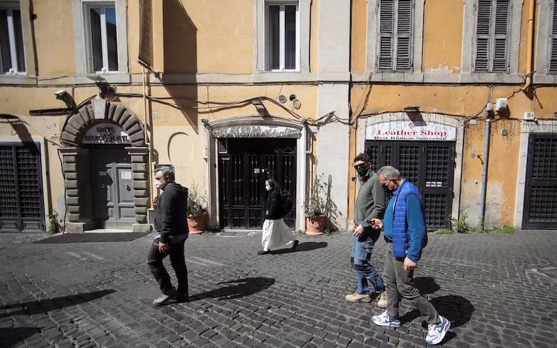 Ảnh minh họa: Người dân đeo khẩu trang đi bộ qua các cửa hàng đóng cửa tại Rome, Italy, ngày 30-3-2021, khi các lệnh hạn chế do Covid-19 ở vùng Lazio được nới lỏng. (Ảnh: Reuters)