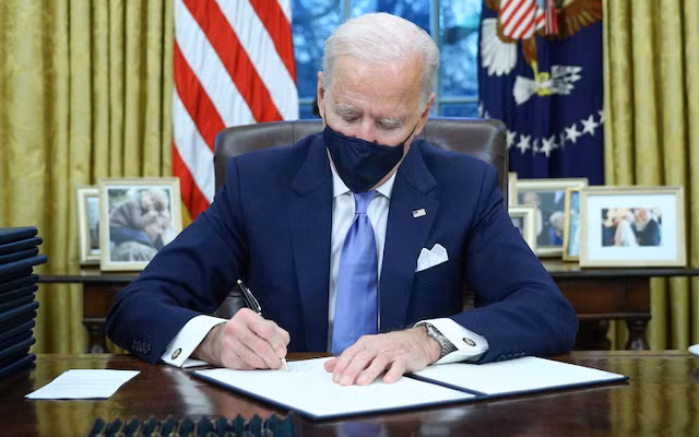 Tổng thống Mỹ Joe Biden ký các sắc lệnh tại phòng Bầu Dục của Nhà Trắng, ở Washington, Mỹ, sau khi ông tuyên thệ nhậm chức ngày 20-1-2021. (Ảnh: Reuters)