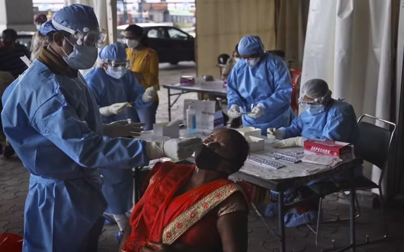 Nhân viên y tế làm xét nghiệm kháng nguyên Covid-19 cho lao động nhập cư tại New Delhi, Ấn Độ, ngày 18-8. (Ảnh: AP)
