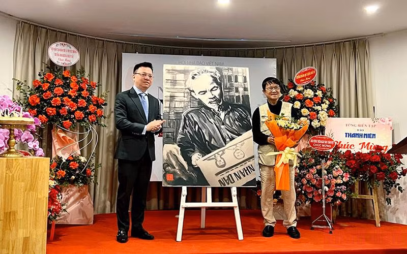 Đồng chí Lê Quốc Minh thay mặt Hội Nhà báo Việt Nam nhận bức vẽ “Bác Hồ đọc Báo Nhân Dân” do tác giả Huỳnh Dũng Nhân trao tặng.