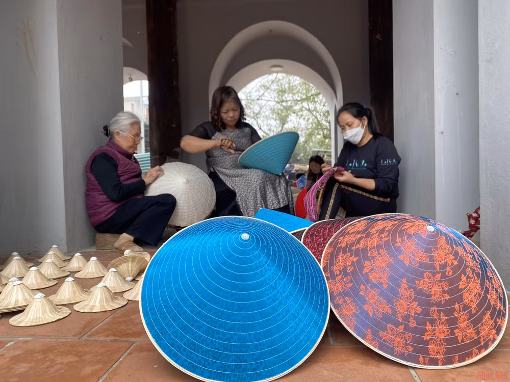 Các nghệ nhân làng Chuông gia công nón cho các diễn viên múa. (Ảnh: MINH NGHĨA)