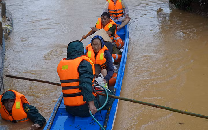 Lực lượng chức năng huyện Cam Lộ (Quảng Trị) đưa người già, trẻ em ra khỏi vùng ngập lũ.