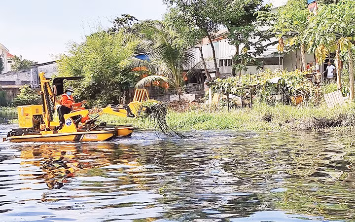 Công nhân Công ty cổ phần Công trình giao thông Sài Gòn vận hành thiết bị thu gom rác, lục bình trên sông Vàm Thuật, quận Gò Vấp.
