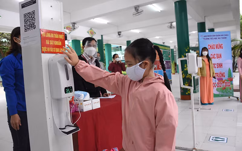 Học sinh lớp 1 Trường Tiểu học Núi Thành (Đà Nẵng) đo thân nhiệt, rửa tay sát khuẩn trước khi vào lớp.