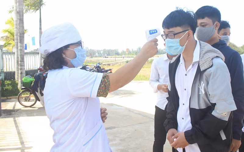 Thí sinh Trường THPT Hùng Vương (huyện Thăng Bình) được kiểm tra nhiệt độ khi đến làm thủ tục dự thi.