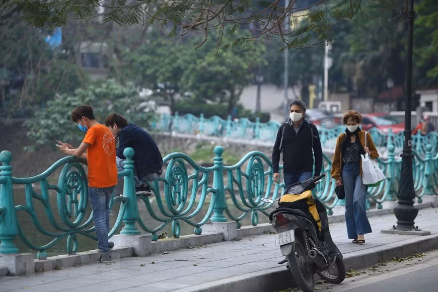 Du khách nước ngoài đi dạo bên đường quanh Hồ Tây. Ảnh: TTXVN.