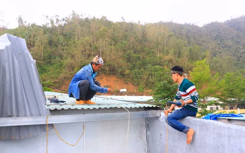 Anh Nguyễn Văn Thuận (bìa trái) sửa mái tôn cho một gia đình.