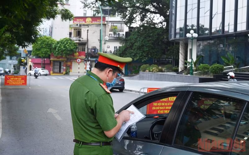 Lực lượng chức năng quận Ba Đình kiểm tra giấy đi đường của người dân tại chốt kiểm soát phòng chống dịch Covid trên đường Thanh Niên. (Ảnh: DUY LINH) 