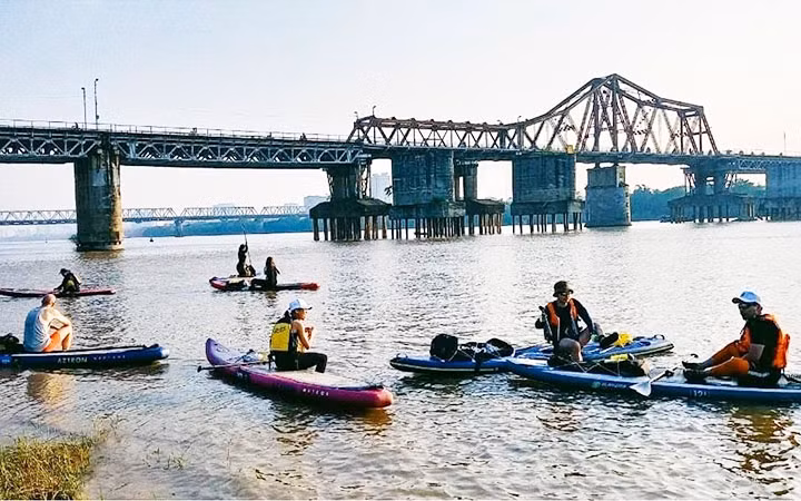 Khách du lịch tham gia tua du lịch chèo SUP trên sông Hồng.